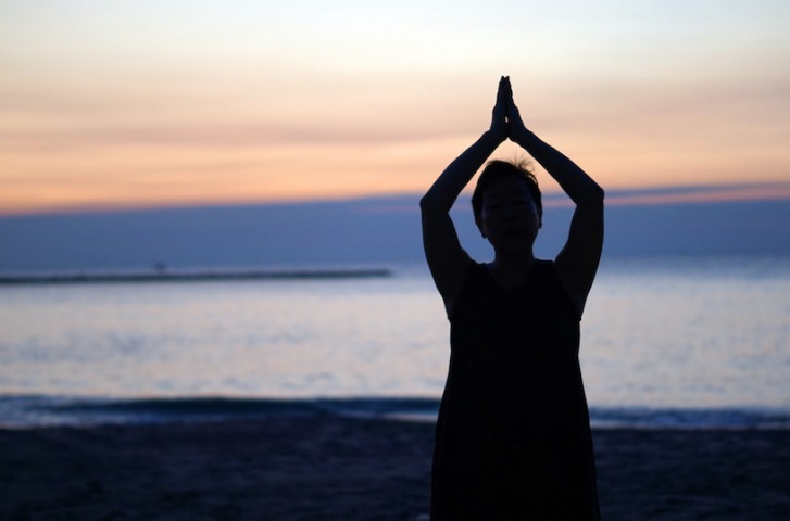 woman meditating on the beach