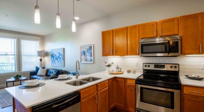 Model kitchen at our senior living apartments in Denver, CO, featuring wood grain cabinetry and stainless steel appliances.