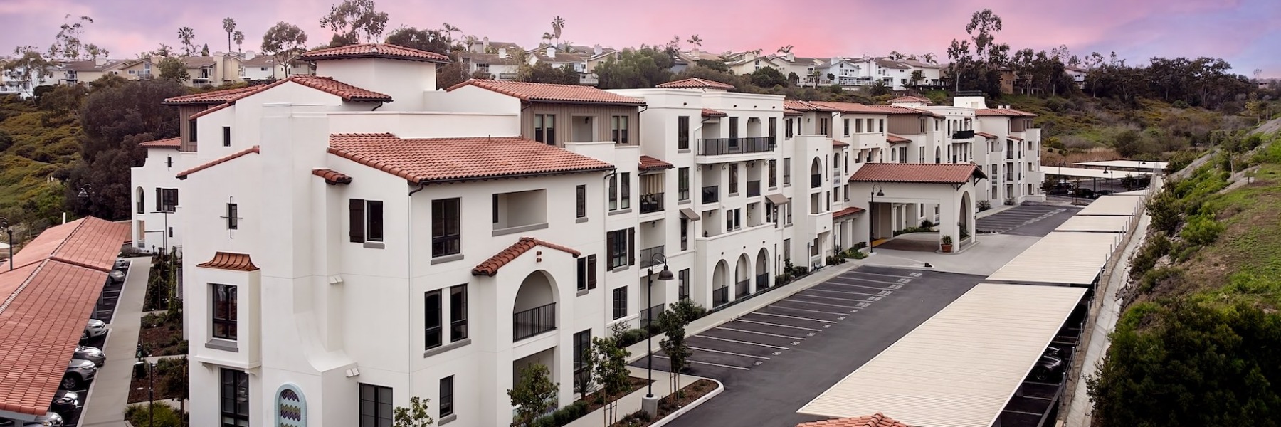 The exterior of Everleigh San Clemente Apartments in Orange County, featuring a spanish style building with parking spots.