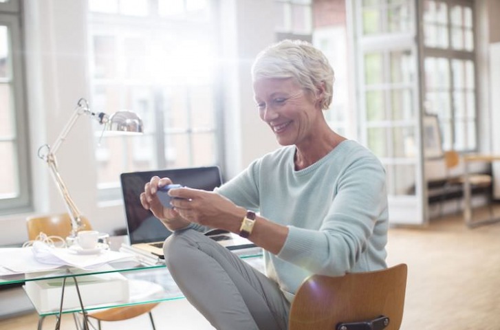 senior woman playing on cellphone at home 