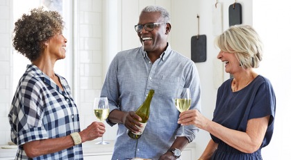 three friends laughing with wine around charcuterie board 