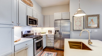 Model kitchen at our apartments in Naperville, featuring wood grain floor paneling and stainless steel appliances.