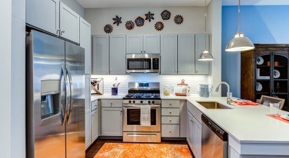 Model kitchen at our apartments in Naperville, featuring wood grain floor paneling and stainless steel appliances.