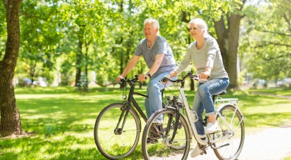 older couple bicycles through park