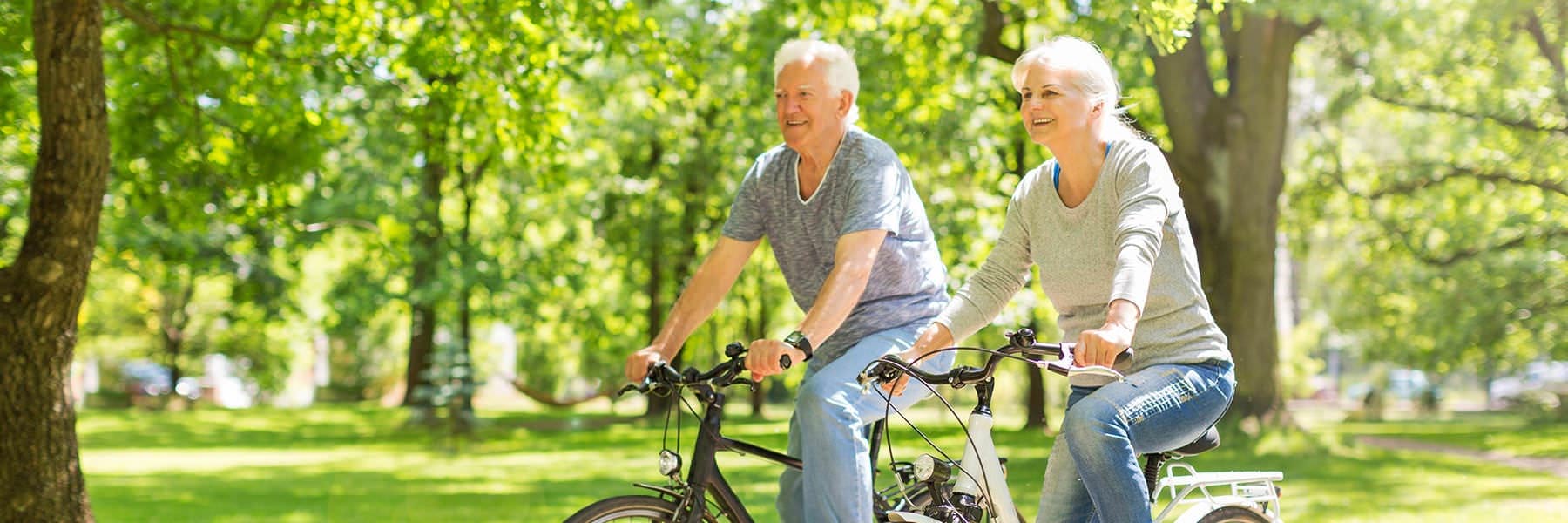 older couple bicycles through park