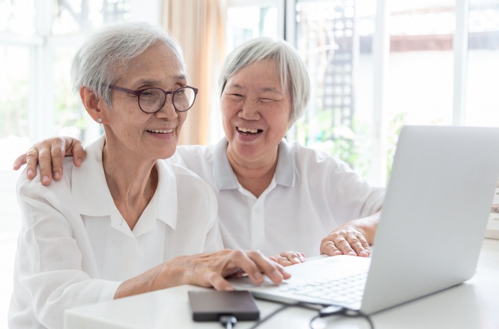 two-white-haired-older-females-on-laptop-smiling-Overture